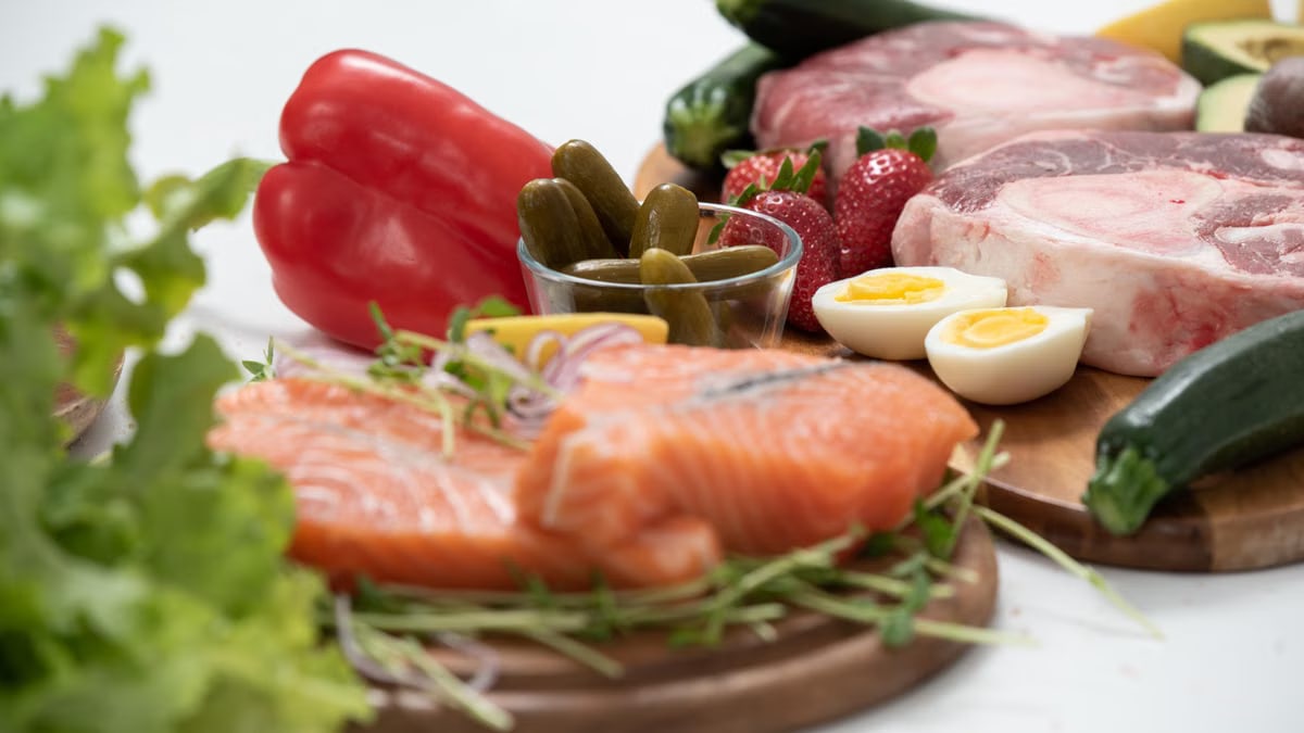 A vibrant assortment of fresh salmon, eggs, vegetables, and fruits arranged on a wooden platter.